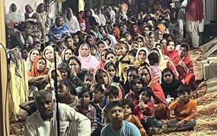 A crowd of women and children seated close together at an evening gathering