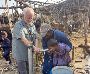 Ray Centanni at a newly drilled water well as a child drinks fresh running water