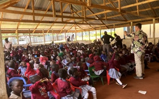 Hundreds of schoolchildren in uniform gathered under a large open-air pavilion