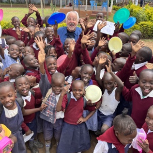 Ray Centanni surrounded by dozens of joyful schoolchildren waving colorful flying discs
