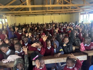 Schoolchildren in uniform smiling and waving in a classroom in Kenya